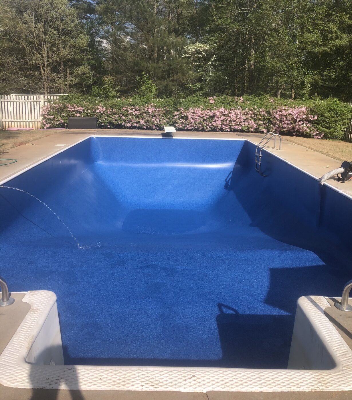 The same rectangular pool with a brand new blue vinyl liner installed and filling
