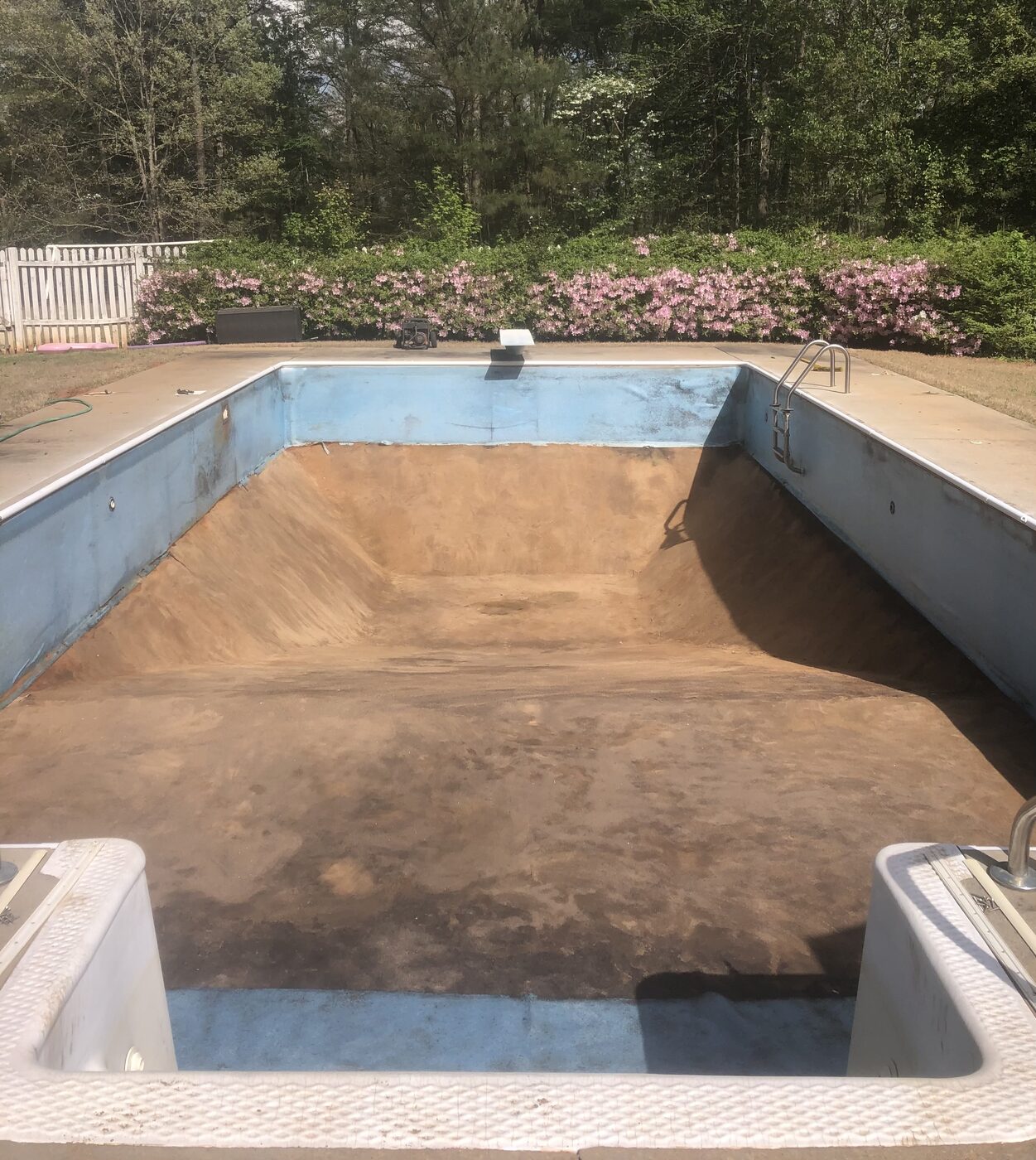 Drained rectangular inground pool stripped down to the bare floor and walls